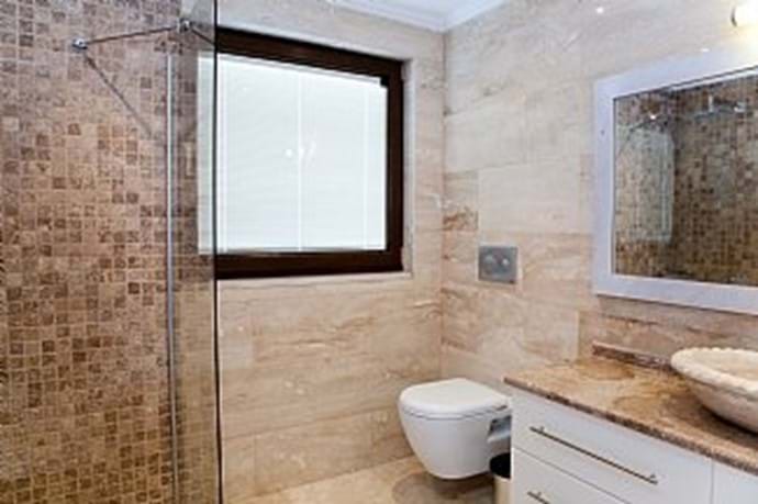 All of the bathrooms are finished in modern travertine/marble